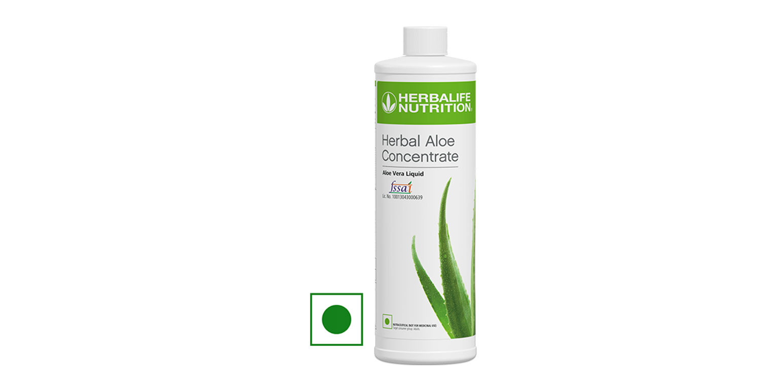 Glass bottle of aloe vera drink surrounded by fresh aloe leaves